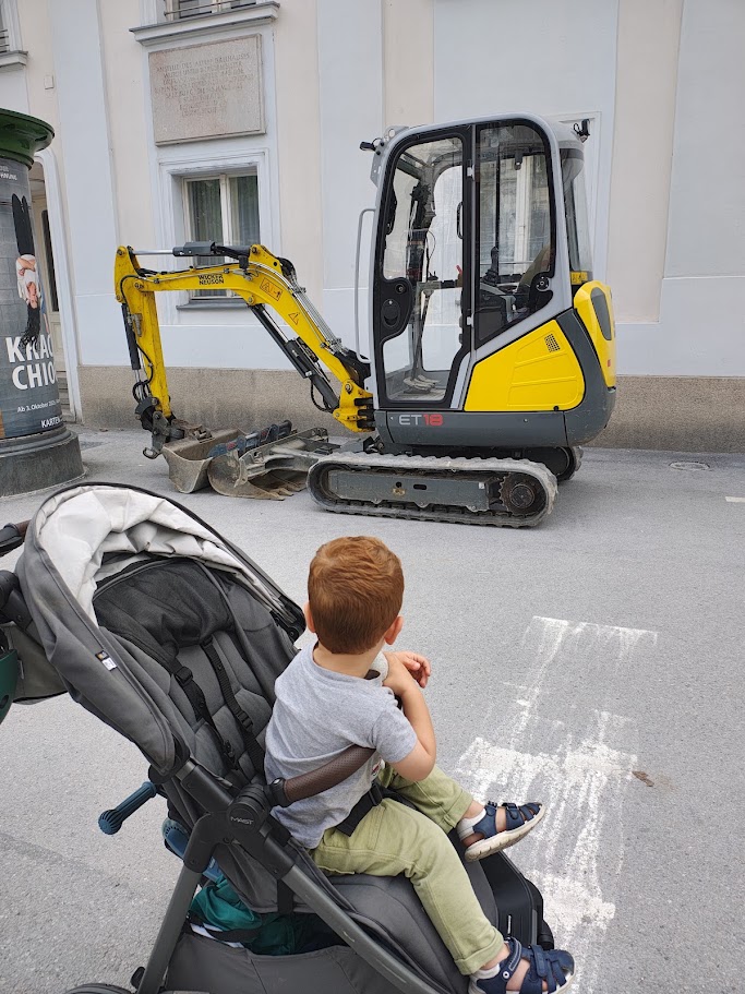 Un bambino osserva incuriosito un mini escavatore cingolato