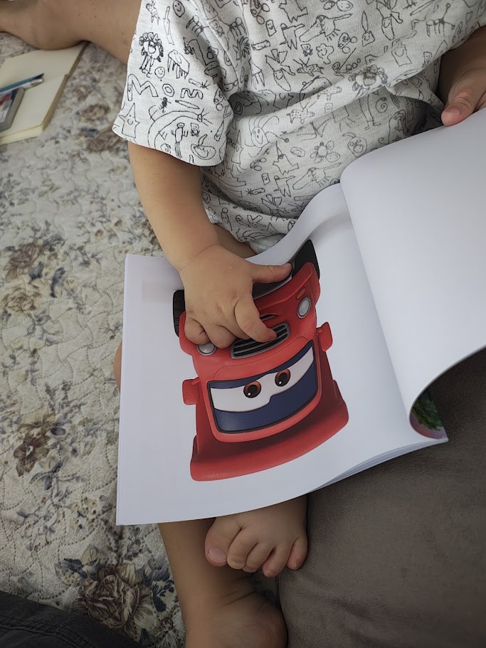 Un bambino sfoglia con curiosità il libro illustrato di Bruno il camion